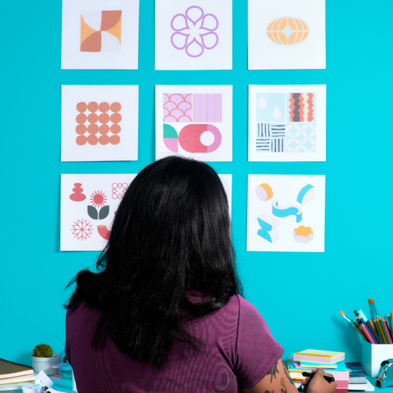 Woman facing a blue wall with digital design elements, working at a table.